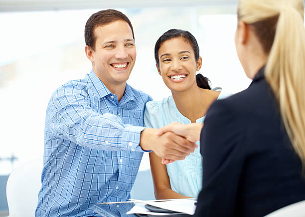 A pleased young couple shaking hands with their financial advisor